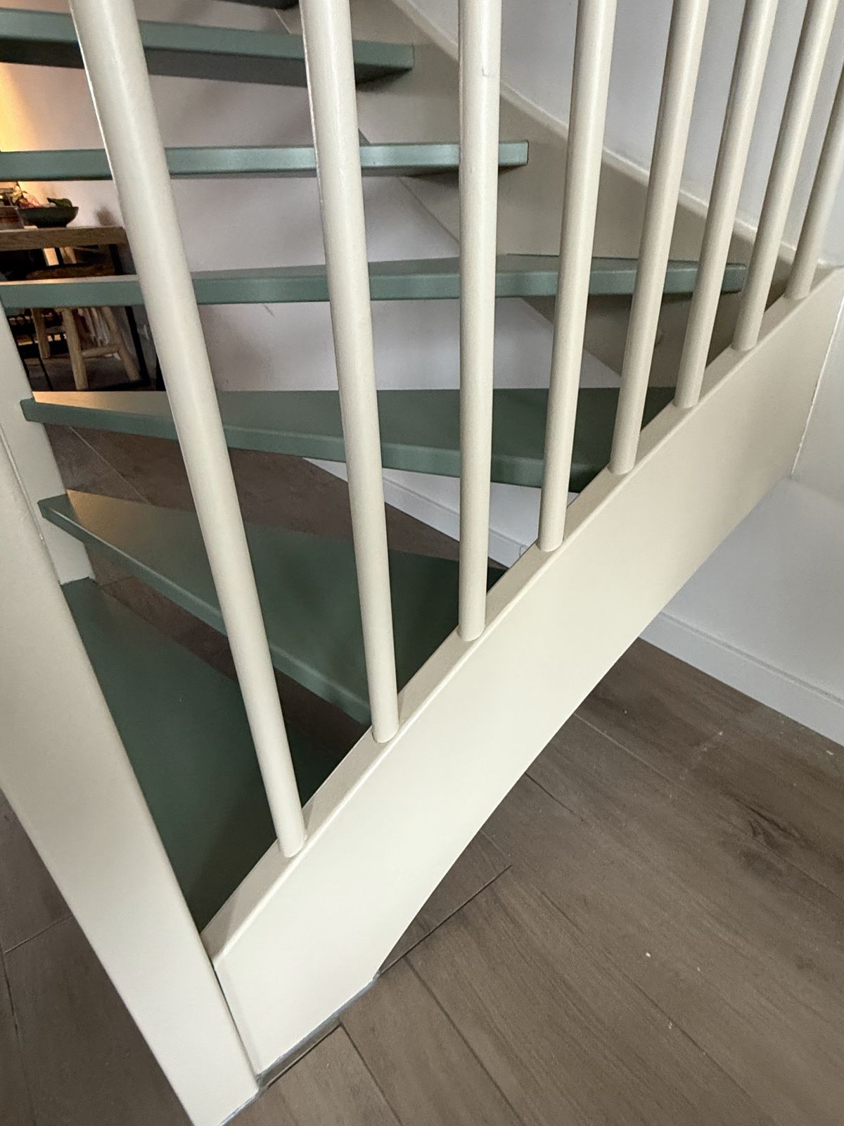 Detail van een trap: witte spijlen en groen geschilderde treden