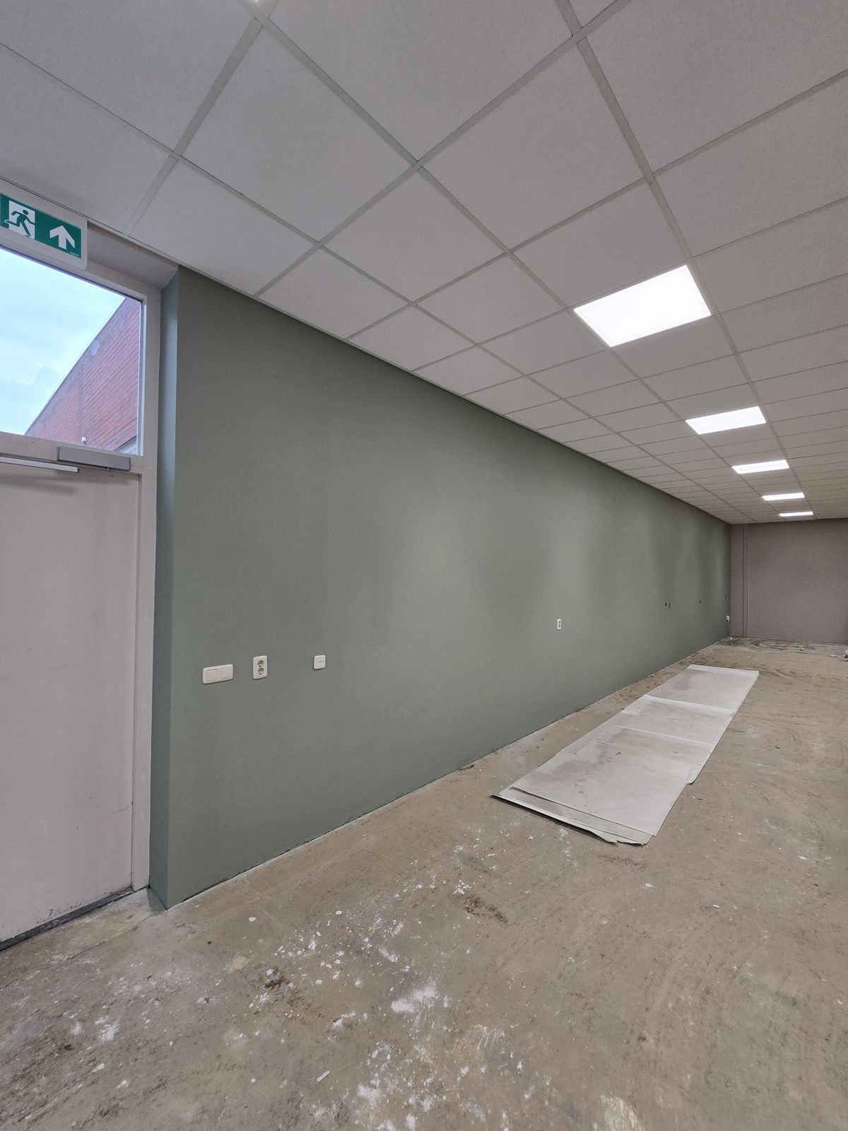 Praktijkruimte met een groene wand, net geschilderd